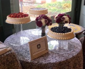 dessert table with three cakes on tall stands and flowers