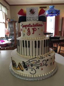 tall music theme cake with congratulations written on it