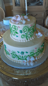 white cake with pale pink flowers and bright green design