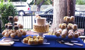 wedding desserts table with three plates of cupcakes and cake in the middle