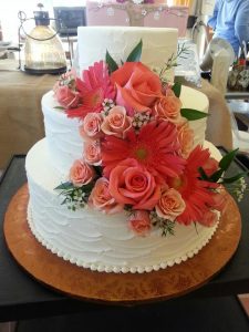 plain white wedding cake with coral flowers
