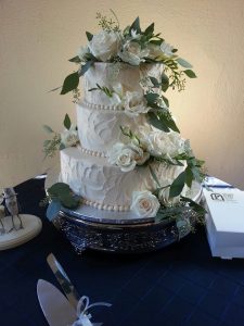 dramatic tiered wedding cake with white roses and greens accents