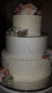 Layered wedding cake with monogram and live flowers