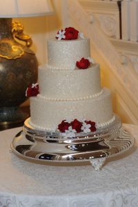 white shiny wedding cake with red roses