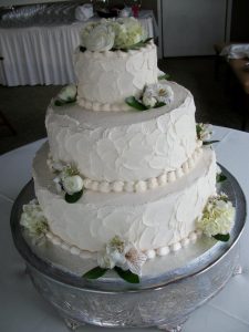 white three tier wedding cake with live flowers