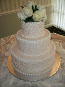 three tier wedding cake with roses on top